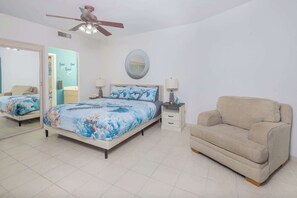 A bedroom with a bed, a chair, a ceiling fan, a mirror, and a nightstand. - Sonoran Spa E302 Beachfront 2BR Condo (Puerto Peñasco)