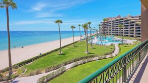 Un resort con playa, zona de piscina y edificio de hotel.