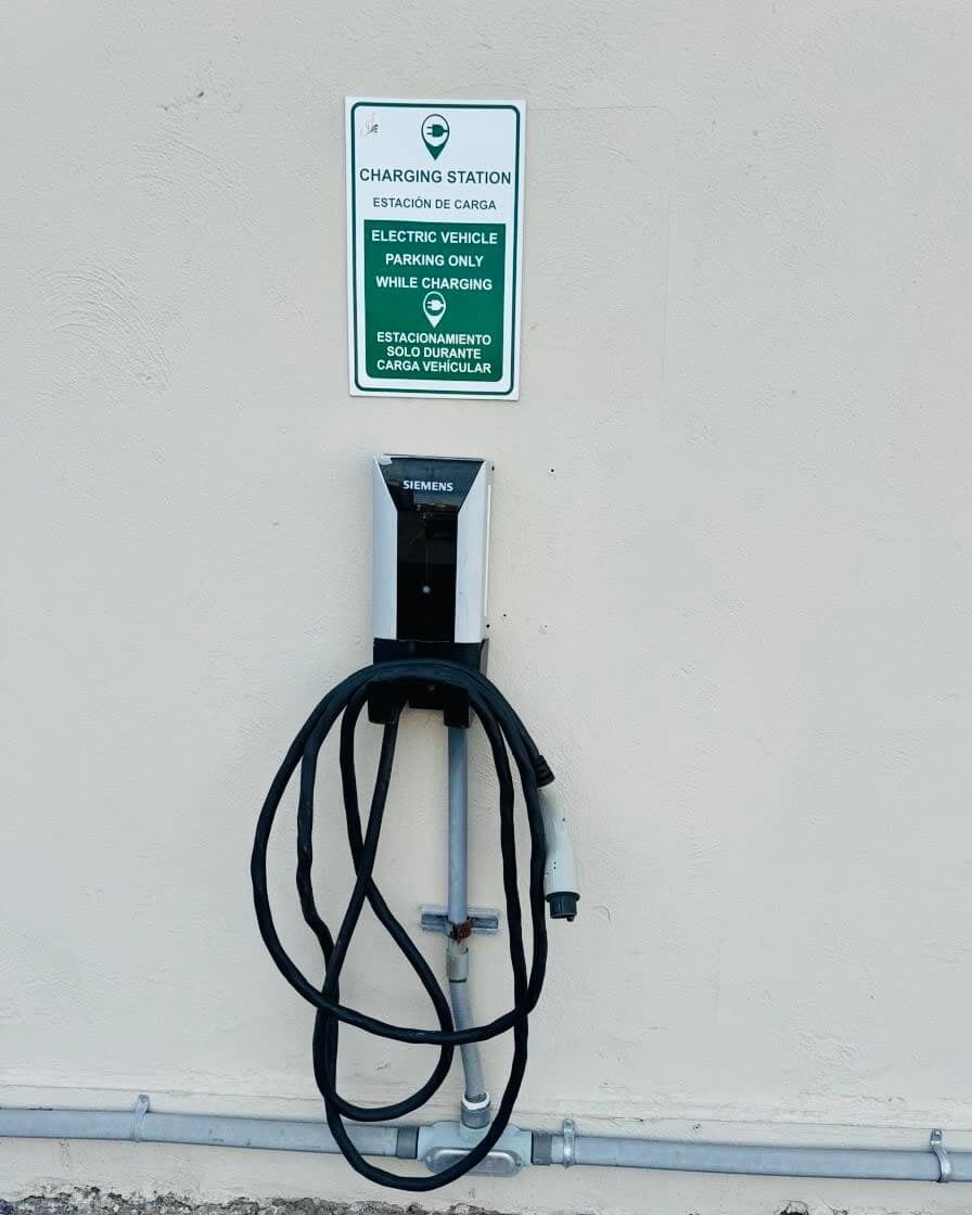 Een oplaadstation met een Siemens-aansluiting en een bord waarop staat dat het alleen voor elektrische voertuigen is tijdens het opladen.