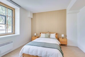 A bedroom with a bed, two bedside tables, a window, and a wall with vertical lines. - 209 Cook - Apartment in Old Quebec (Québec)