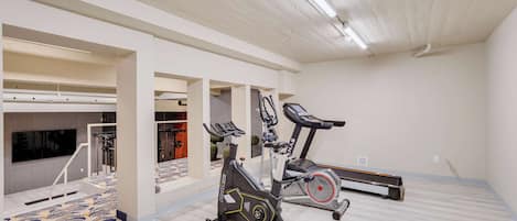 Un gimnasio con equipo de ejercicios, una cinta de correr y una bicicleta estática.