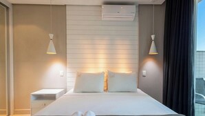 A hotel room with a bed, bedside tables, an air conditioning unit, and pendant lights. - Apt. w/ Balcony in Condo. w/ Pool Lvt0031 (Brasília)