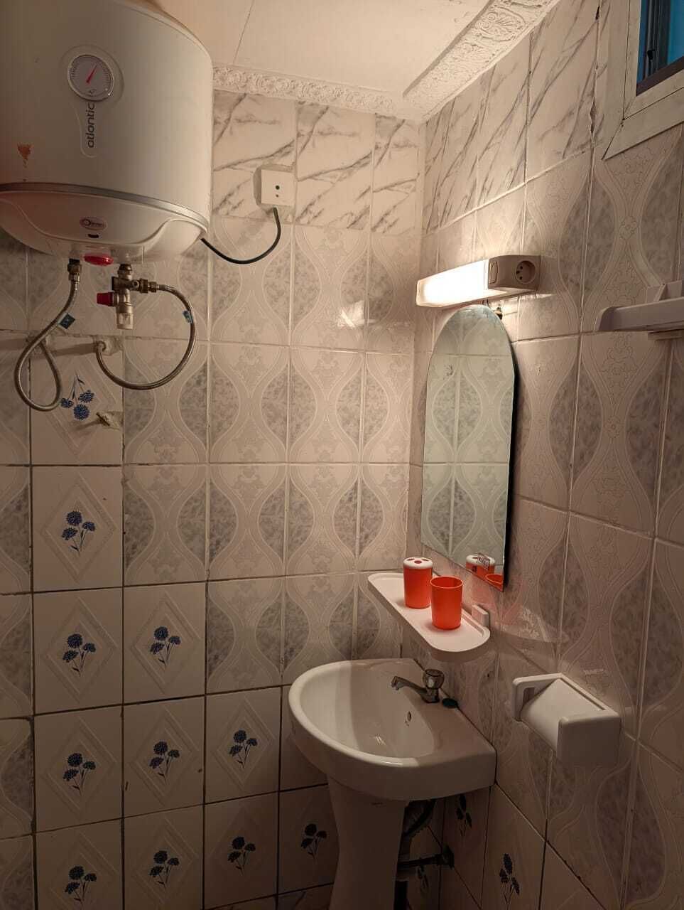 Ein Badezimmer mit einem weißen Waschbecken, einem Spiegel und einem Wandheizkörper.