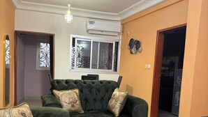 A living room with a green sofa set, a round coffee table, and a TV. - Premium 2 Bedroom Apt | Plus Parking & Views (Yaoundé)