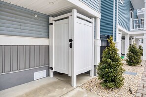 Ein weißer Außenschrank an einem grauen Haus mit einem Metallgitter.