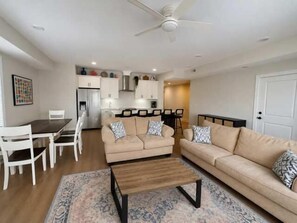 A living room with a sofa, coffee table, and a dining area with chairs and a table. - Kays Oasis 13 Wildwood (Wildwood)