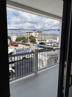 A balcony with a view of a construction site, a sign for 'ABSOLUTE MECHANICAL,' and a fenced area with parked vehicles. - Kays Oasis 13 Wildwood (Wildwood)