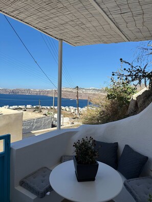 Un balcon avec vue sur la mer et un bâtiment blanc qui se dessine à l’horizon.