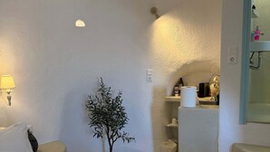 Ein Hotelzimmer mit einem Bett, einer kleinen Topfpflanze, einem Badezimmer mit Waschbecken und Spiegel sowie einer Treppe.