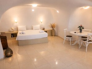 Ein modernes Schlafzimmer mit einem großen Bett, Nachttischlampen, einem kleinen Tisch mit Stühlen und einer dekorativen Vase.