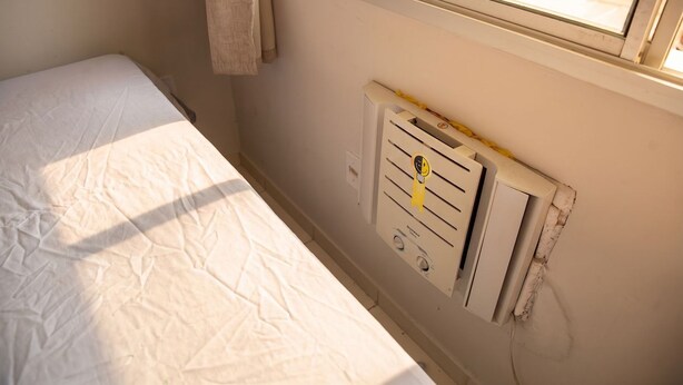 Una cama individual con un colchón blanco en una habitación con ventana.