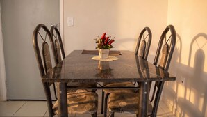 Una mesa de comedor con cuatro sillas, una planta pequeña en maceta y un mantel individual.
