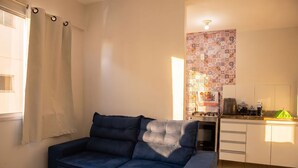 Un espacio habitable pequeño con sofá, kitchenette y pared con diseño.