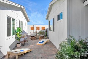 A courtyard with a wooden table, chairs, and potted plants. - 7BR Scottsdale Retreat | Pool, Casita & Lawn Games (Scottsdale)