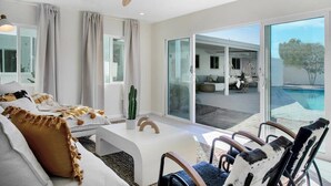 Een moderne woonkamer met een bank, fauteuils, een salontafel en een plafondventilator.