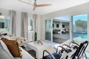 Ein modernes Wohnzimmer mit Sofa, Sesseln, Couchtisch und Deckenventilator.