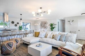 Ein modernes Wohnzimmer mit einem weißen Ecksofa, einem Couchtisch und einem Essbereich mit Stühlen.
