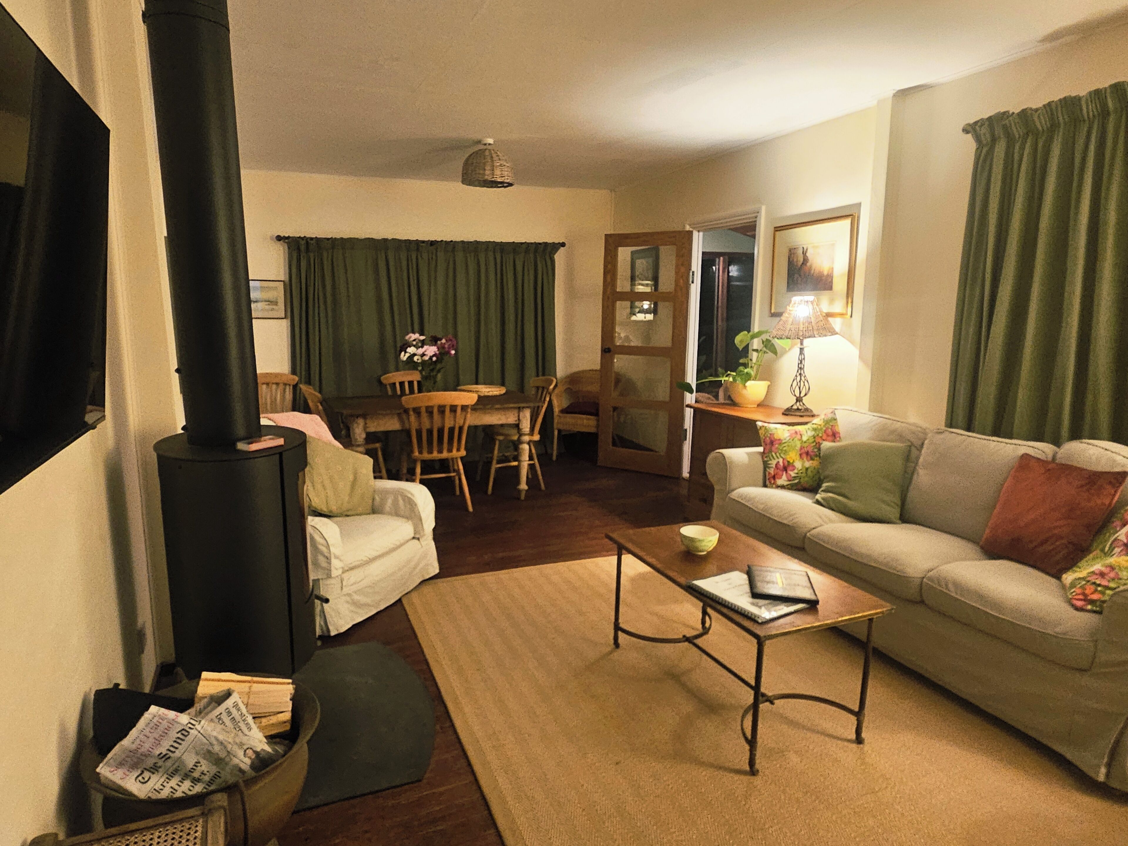 A cozy living room with a fireplace, a sofa, a coffee table, and a dining area with chairs and a table.
