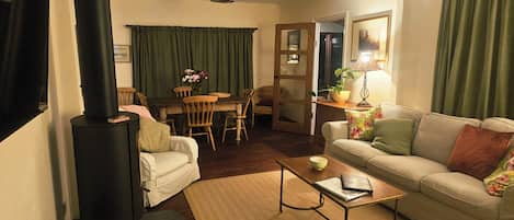 A cozy living room with a fireplace, a sofa, a coffee table, and a dining area with chairs and a table.