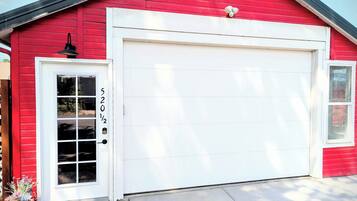 A red building with a white garage door, a white door with a window, and a mailbox on the right side.