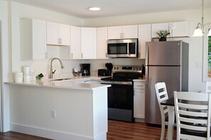 A modern kitchen with white cabinetry, stainless steel appliances, and a wooden island with seating.
