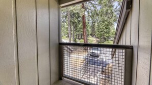 A balcony with a metal railing, a view of a forest, and a parked car in the background. - Condo at Granlibakken Tahoe Resort - Ski-In - Ski-Out with Pool, Spa & Minutes from Lake Tahoe (Tahoe City)