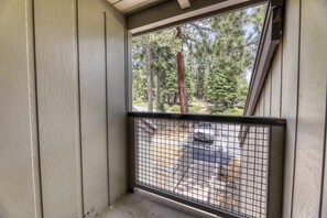 A balcony with a metal railing, a view of a forest, and a parked car in the background. - Condo at Granlibakken Tahoe Resort - Ski-In - Ski-Out with Pool, Spa & Minutes from Lake Tahoe (Tahoe City)