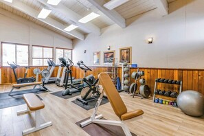 Ein Fitnessstudio mit verschiedenen Trainingsgeräten, darunter Laufbänder, eine Bank und Kraftstationen.