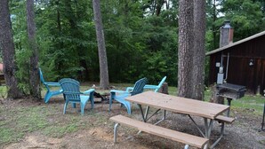Een picknickopstelling met een houten tafel en bankjes, omringd door bomen.