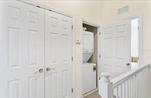 A hallway with white double doors, a laundry room with stacked washers and dryers, and a white railing. - Private Townhouse  - Walk to Hospitals & Downtown St. Pete - 30 MINIMUM RENTAL (St. Petersburg)