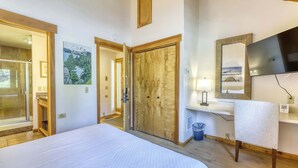 Een hotelkamer met een bed, een houten garderobe, een spiegel, een wastafel en een televisie.