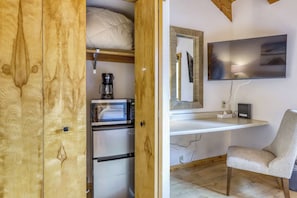 A compact room with a kitchenette, a microwave, a coffee maker, a chair, and a flat-screen TV mounted on the wall. - Cozy Studio at Granlibakken Tahoe Resort - Ski-In - Ski-Out with Pool, Spa & Minutes from Lake Tahoe (Tahoe City)