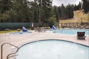 A swimming pool area with lounge chairs and a covered seating area. - Cozy Studio at Granlibakken Tahoe Resort - Ski-In - Ski-Out with Pool, Spa & Minutes from Lake Tahoe (Tahoe City)
