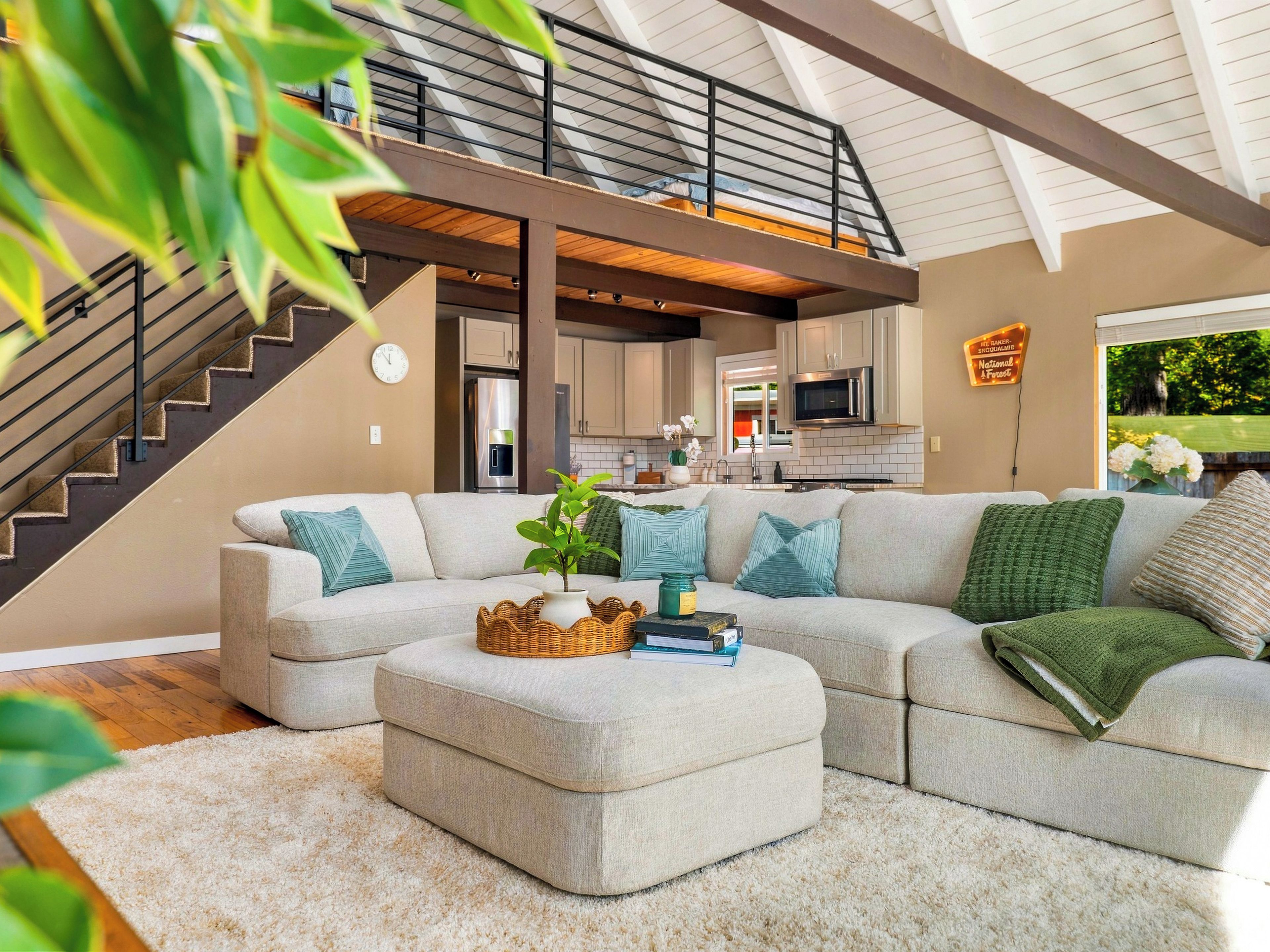 A modern living room with a sectional sofa, a coffee table, and a staircase leading to an upper level.