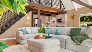 A modern living room with a sectional sofa, a coffee table, and a staircase leading to an upper level.