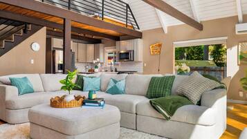 A modern living room with a sectional sofa, a coffee table, and a staircase leading to an upper level.