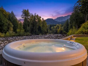 Un bain à remous situé dans un cadre naturel, avec vue sur les montagnes et les arbres.