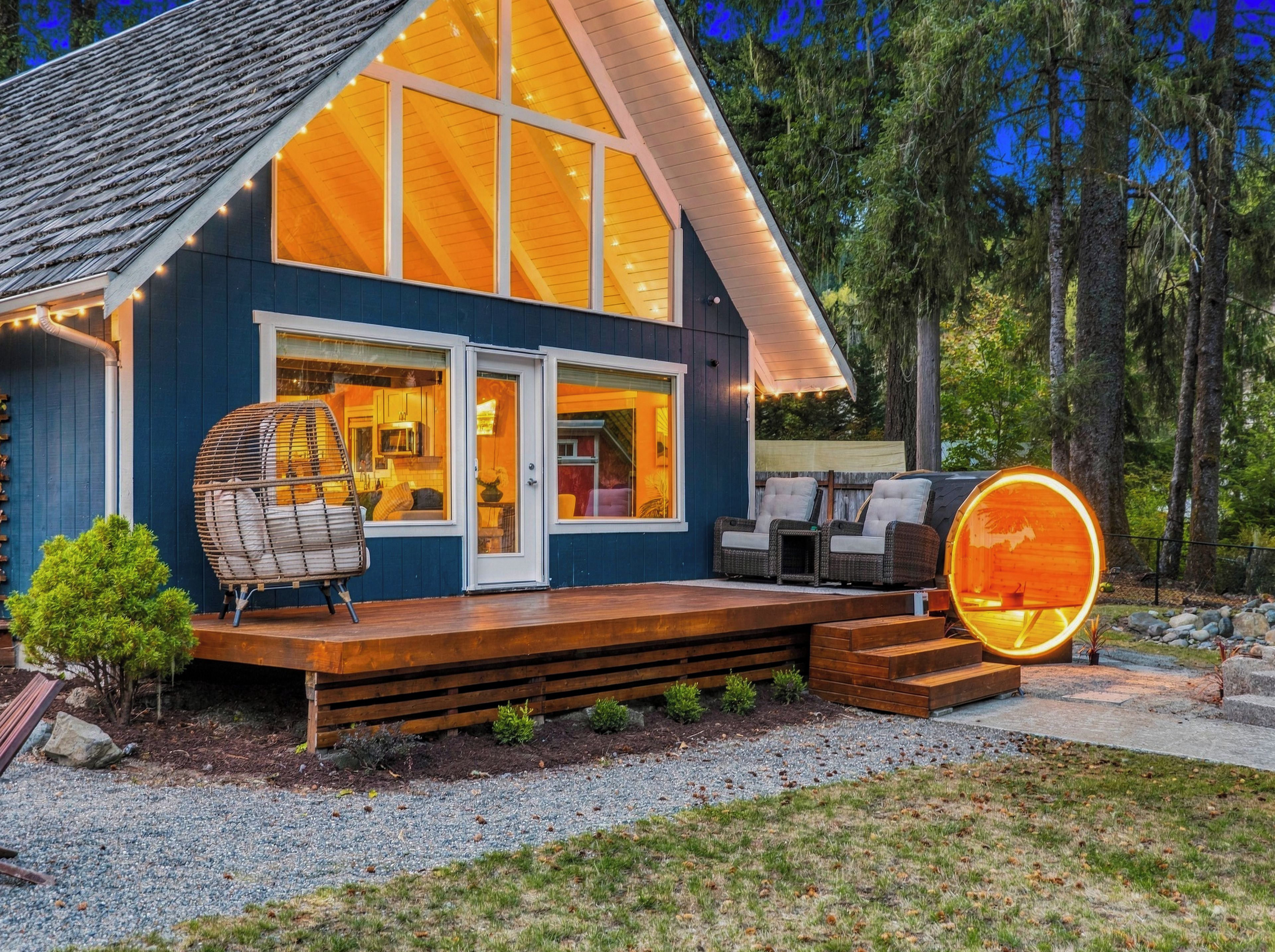 A modern house with a large deck, a cozy interior with a kitchen and living area, and a distinctive circular window.
