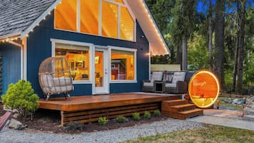 A modern house with a large deck, a cozy interior with a kitchen and living area, and a distinctive circular window.