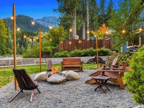 An outdoor seating area with a fire pit, wooden chairs, and a bench.
