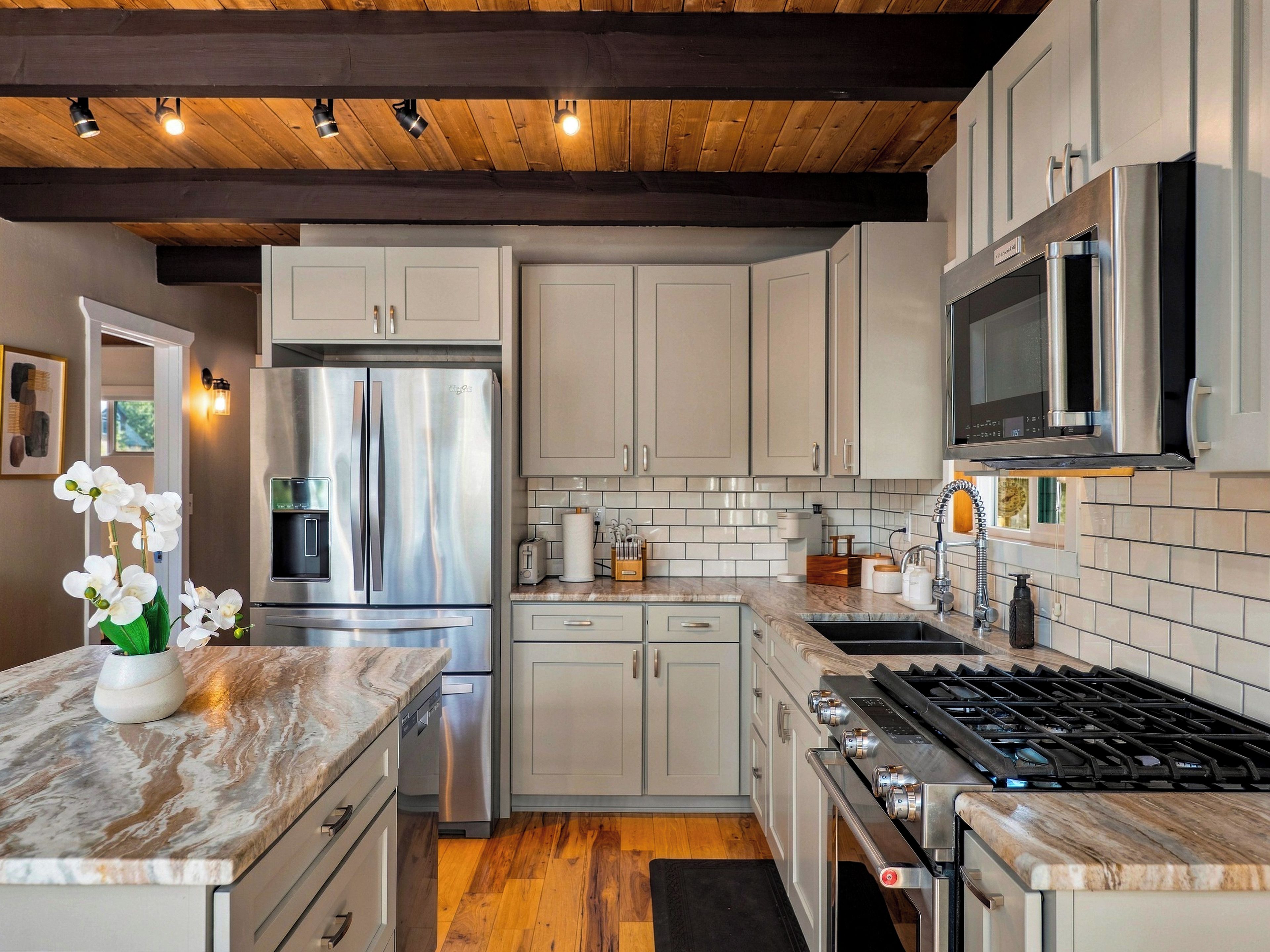 Una cocina moderna con electrodomésticos de acero inoxidable, encimeras de mármol y vigas de madera en el techo.