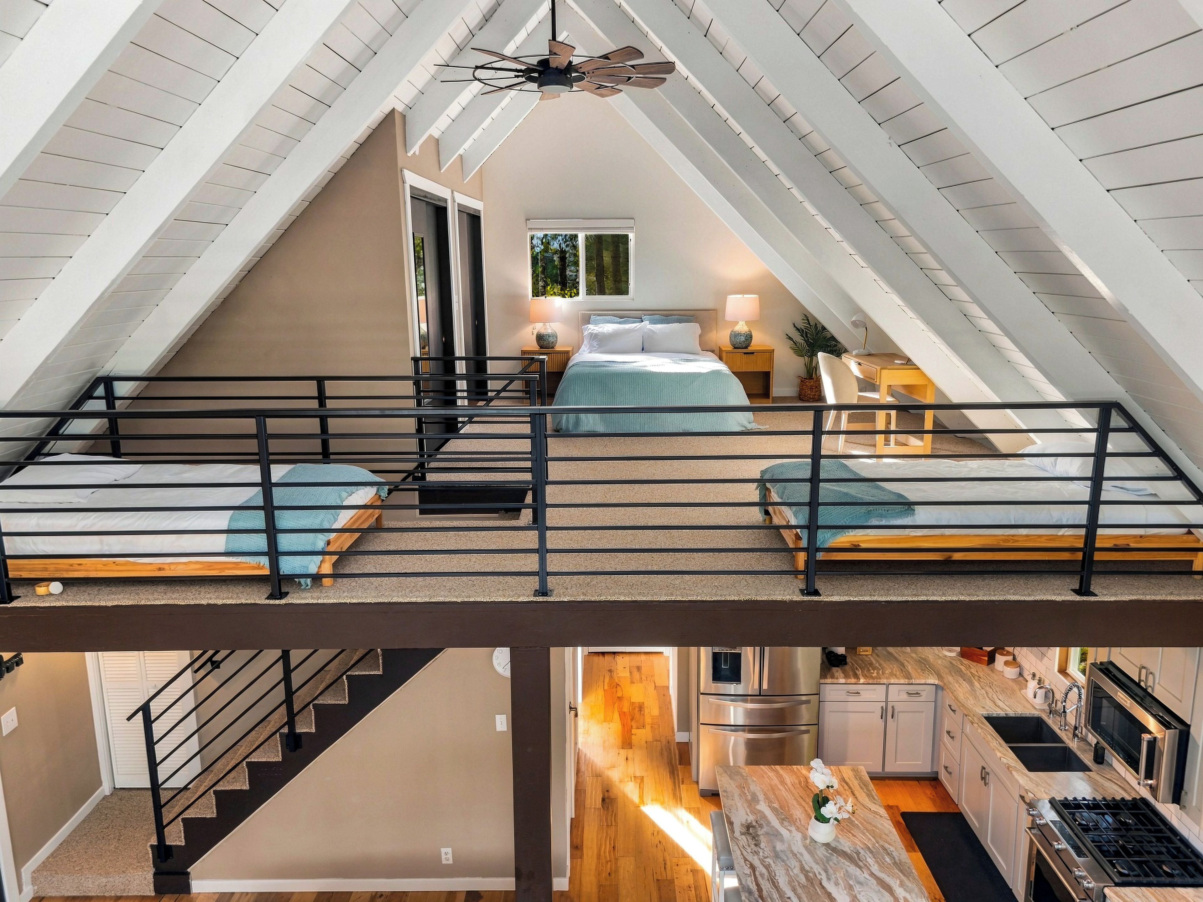 Ein Schlafzimmer mit Schlafgalerie, einer Treppe und einer Küchenzeile.