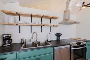 Eine moderne Küche mit Edelstahlspüle, Kaffeemaschine, Backofen und Geschirrspüler.