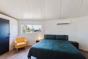 Ein Schlafzimmer mit Bett, Stuhl, Fenster und Klimaanlage.