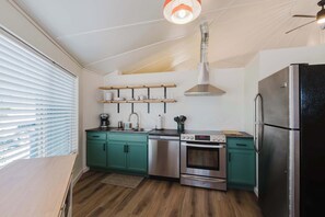Eine moderne Küche mit türkisfarbenen Schränken, einem Edelstahl-Kühlschrank, einem Backofen und einer Kaffeemaschine.
