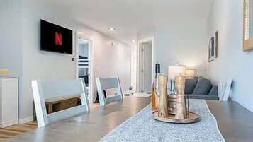 Een moderne woonkamer met een eettafel, een tv aan de muur en een bank.