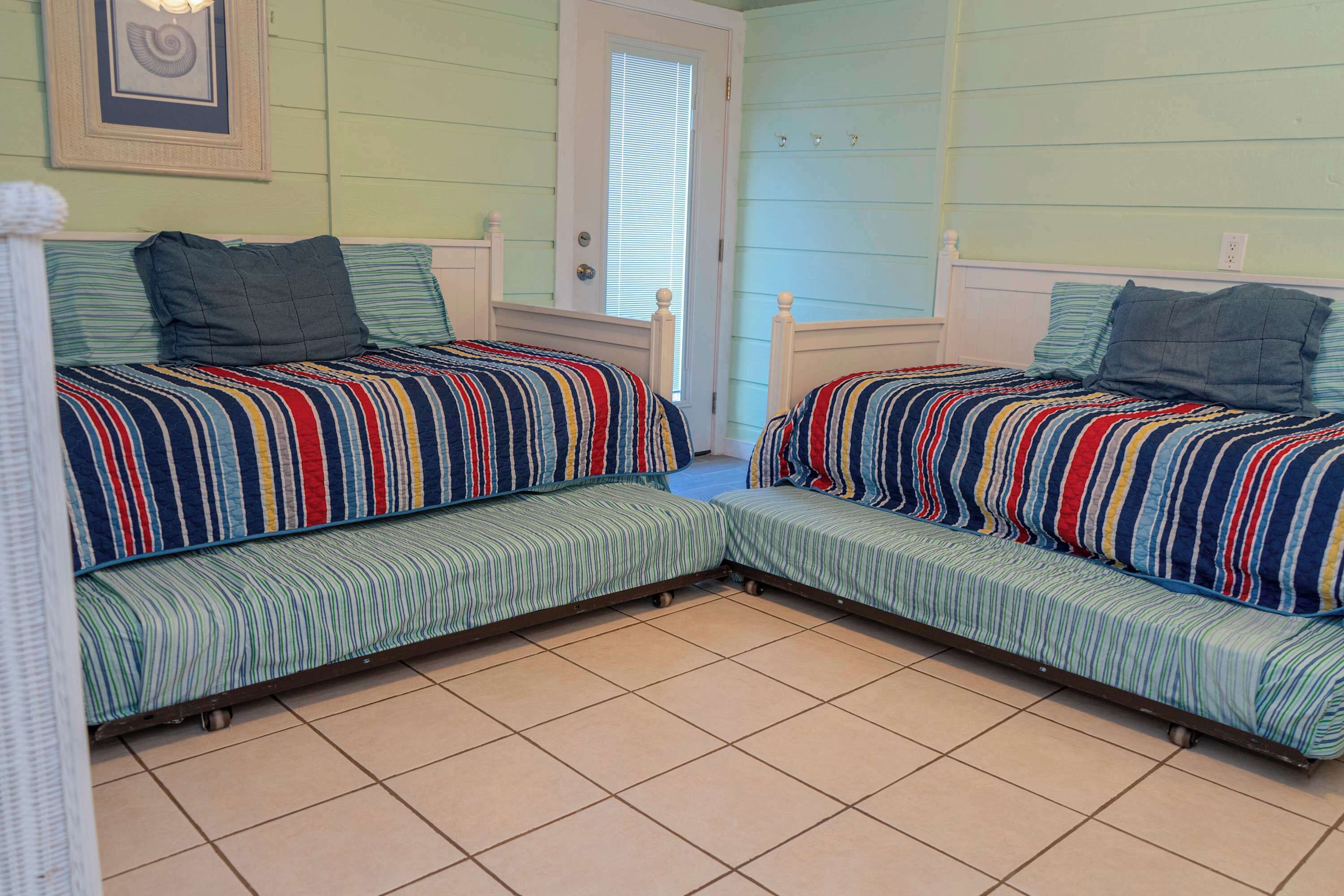 A room with two beds with striped bedding, a door, and a window.