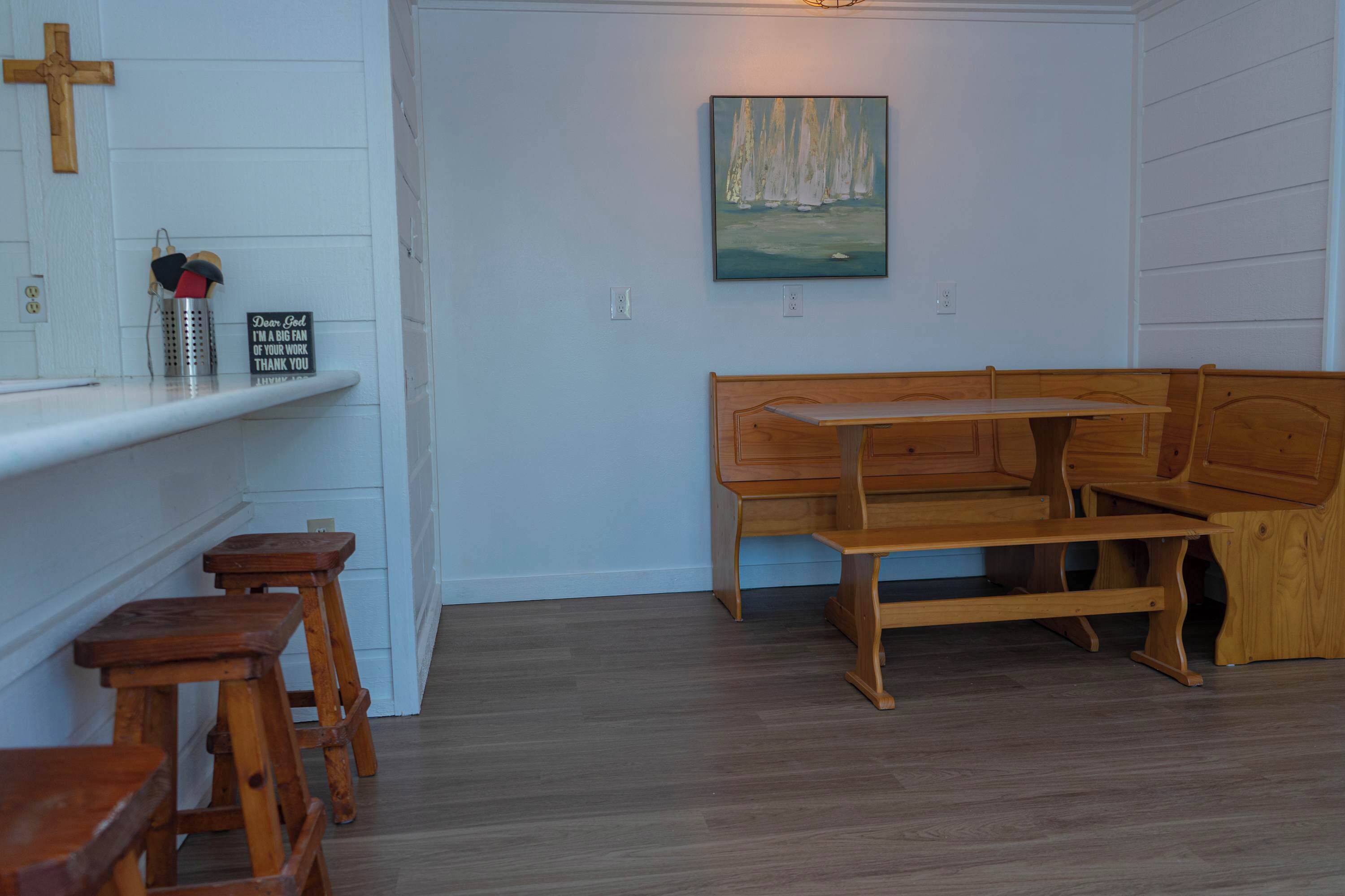 Um quarto com um banco de madeira, uma mesinha e um quadro na parede.