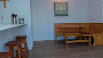 Um quarto com um banco de madeira, uma mesinha e um quadro na parede.