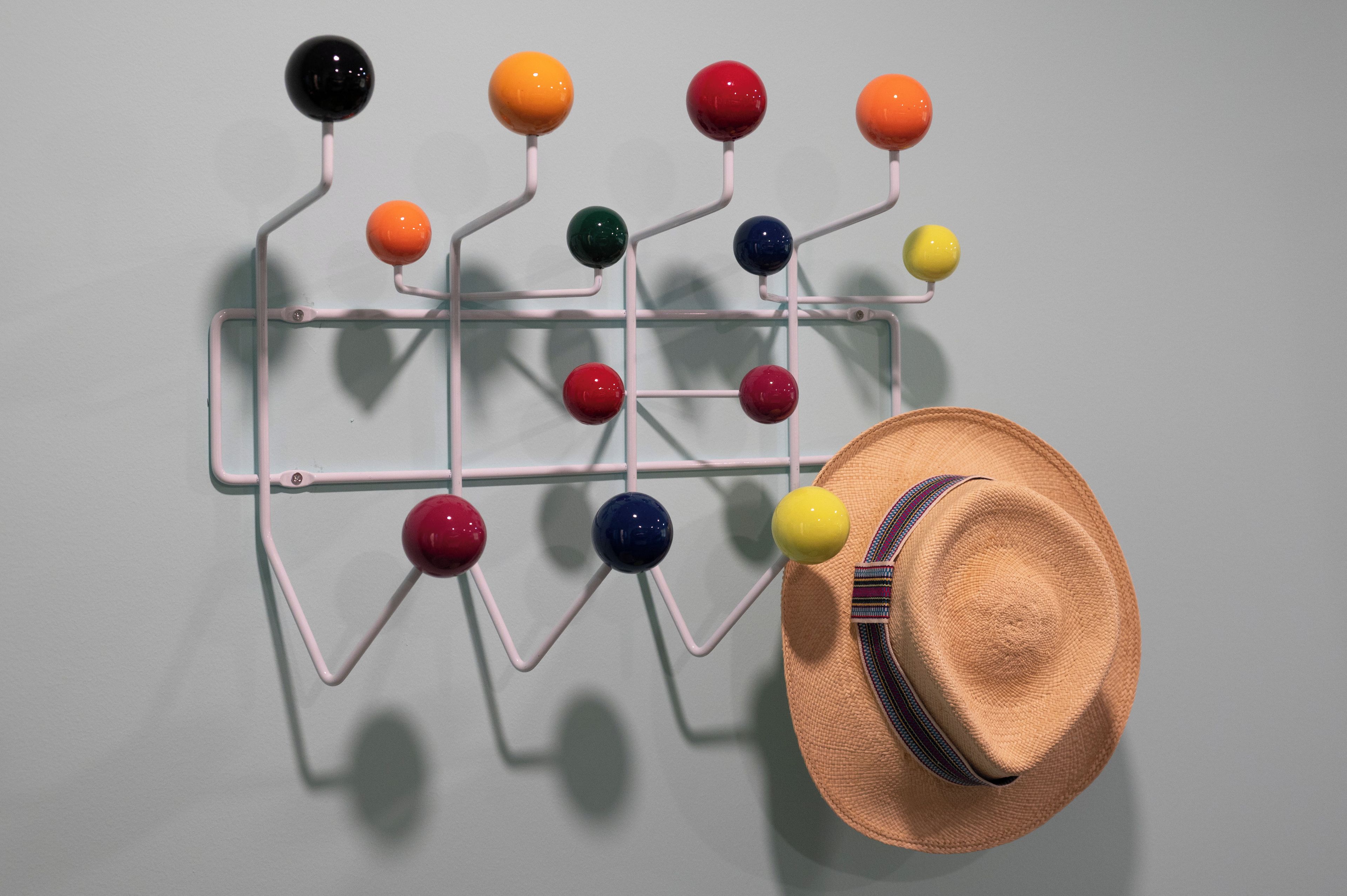 Un présentoir mural avec plusieurs sphères colorées et un chapeau de paille.